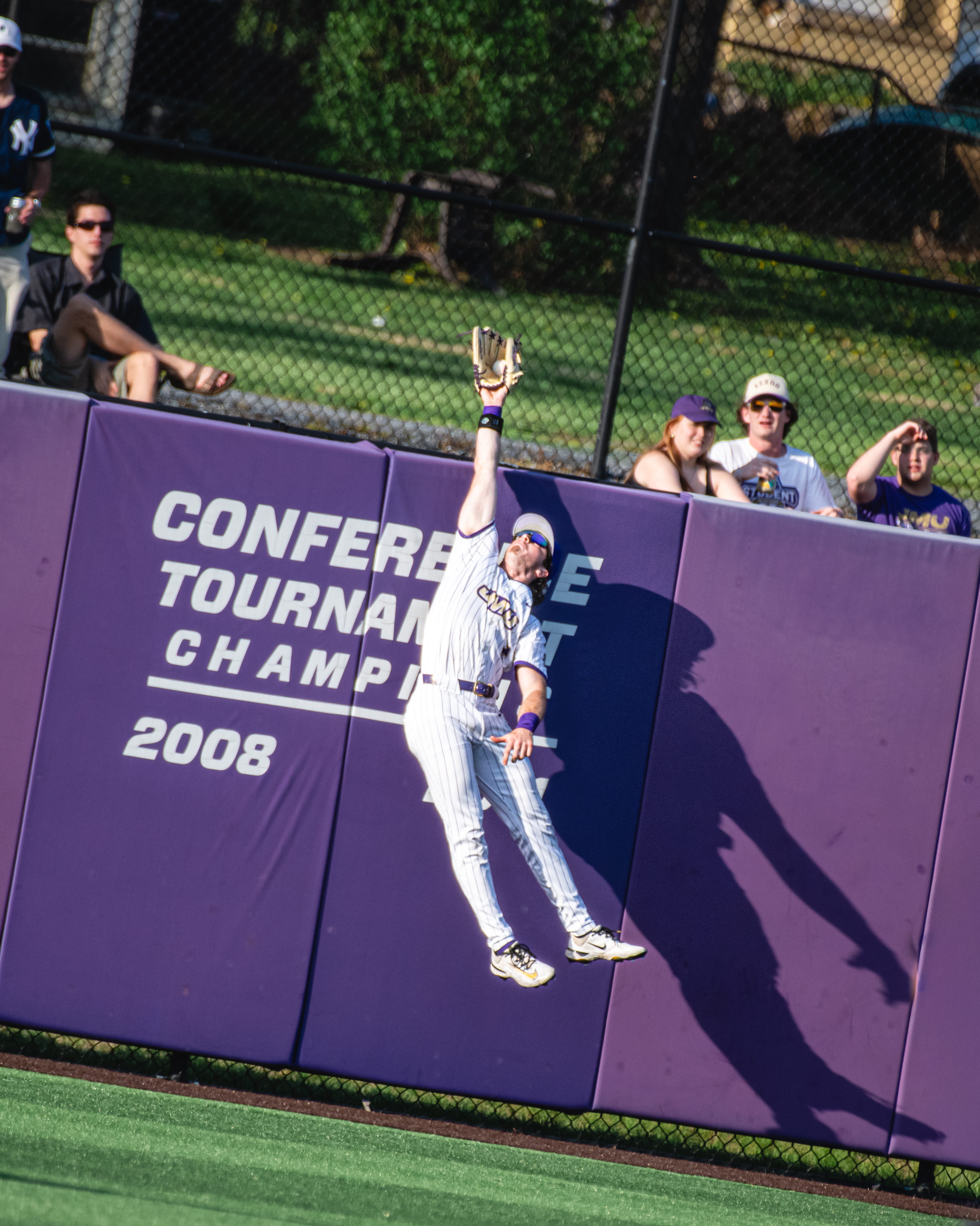 JMU baseball outfielder leaping for a catch near the wall